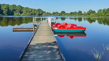 Een houten steiger die zich uitstrekt over kalm water, met een rode boot aan het einde afgemeerd.