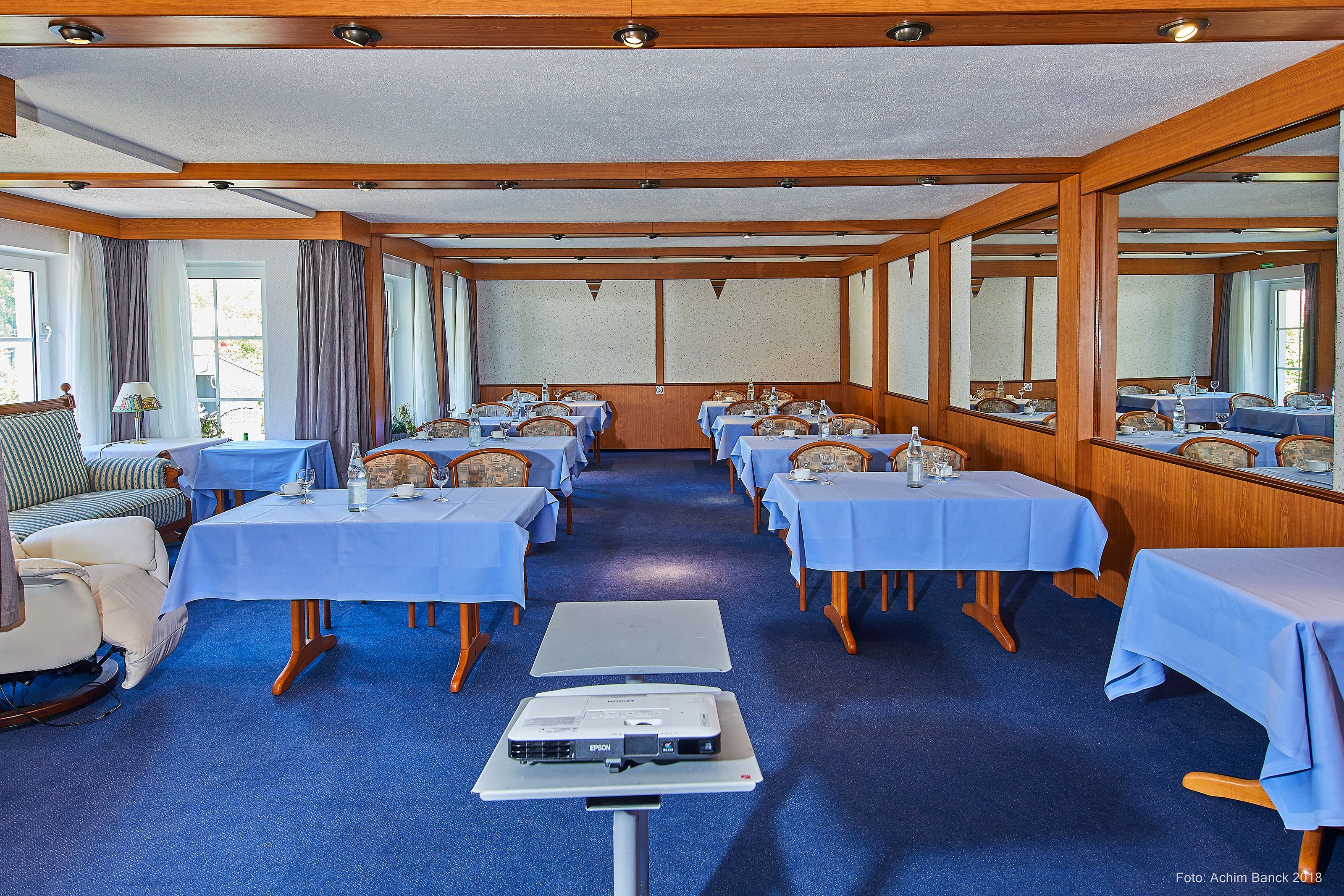 A conference room with multiple tables, chairs, and a projector on a table.