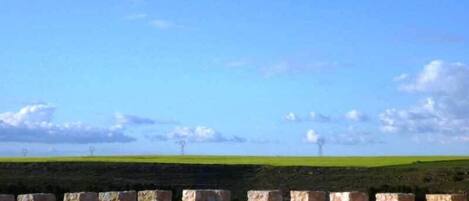 Un muro de piedra con vistas a un campo verde y un cielo despejado.