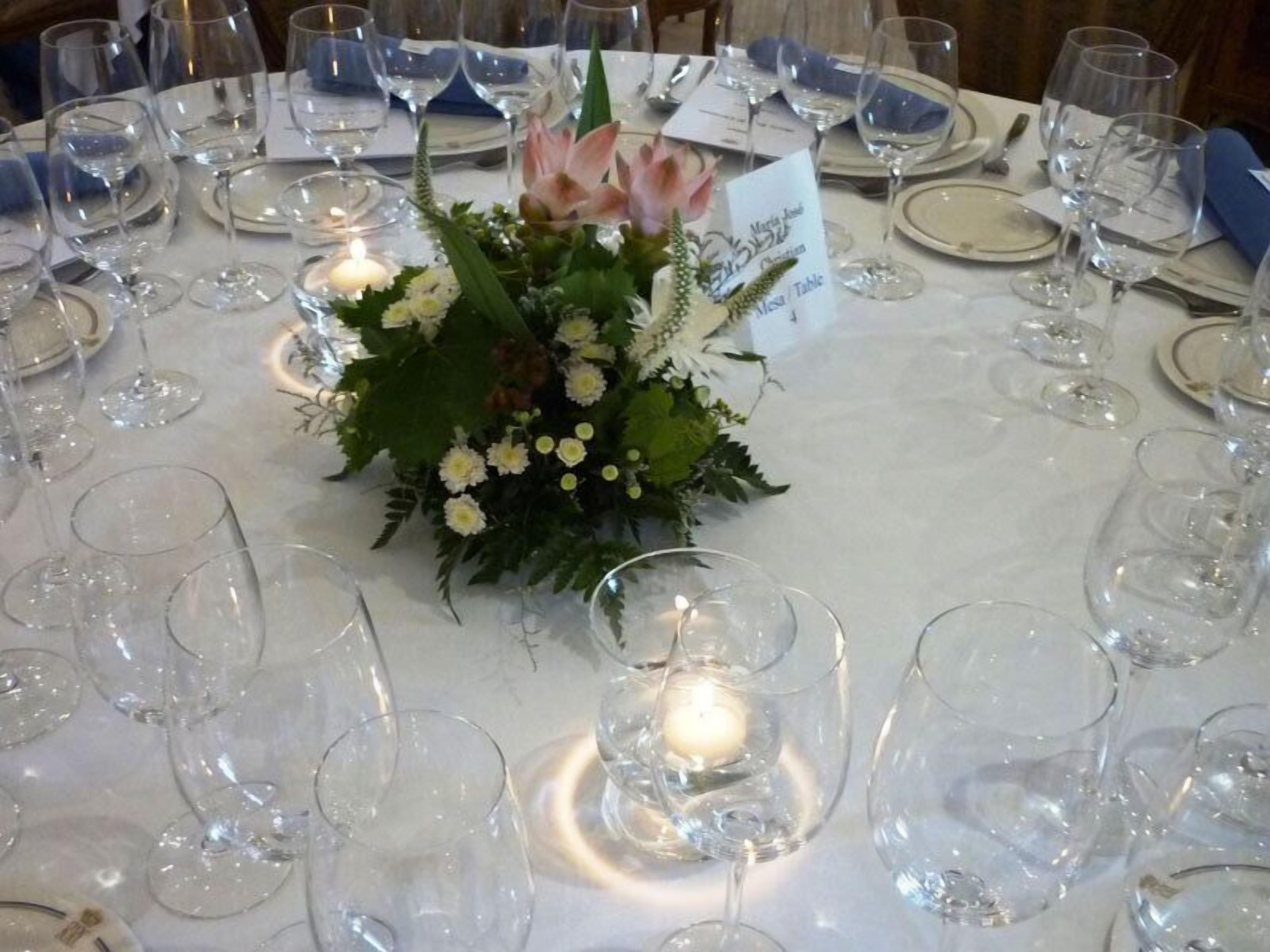 A table set for a formal event with empty wine glasses, a candle, and a floral centerpiece.