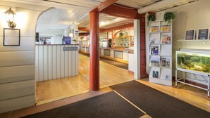 A reception area with a reception desk, a reception sign, a fish tank, and a wall with framed pictures and information boards. - Dala Wärdshus (Rattvik)