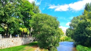 A river with trees and a stone wall on one side. - Urban Burgos (Burgos)