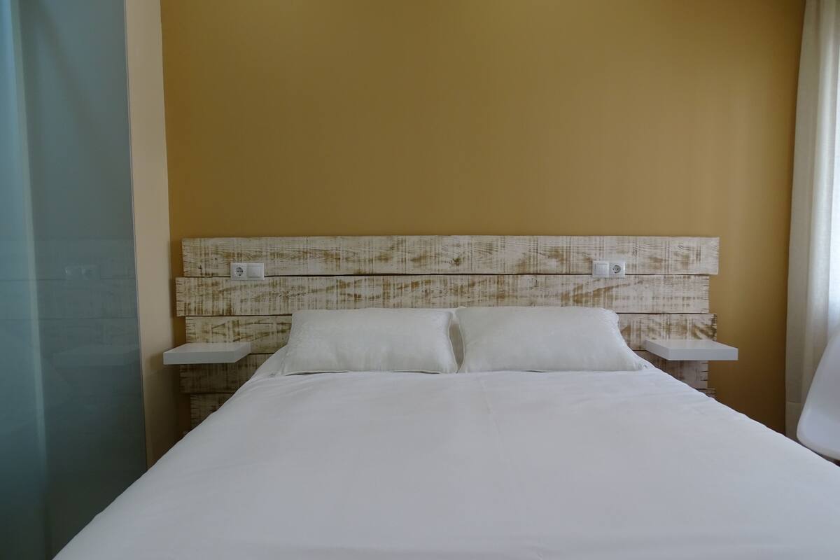 A hotel room with a bed, two bedside tables, and a headboard with a textured design.