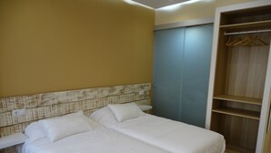 A bedroom with two beds, a wooden headboard, a wardrobe, and a wooden floor. - Urban Burgos (Burgos)