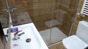 A bathroom with a glass-enclosed shower, a white sink, and a toilet. - Urban Burgos (Burgos)
