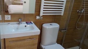 A bathroom with a sink, toilet, and a glass-enclosed shower. - Urban Burgos (Burgos)