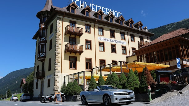 A hotel with a sign reading "SCHWEIZERHOF" and a balcony with a view of the mountains. - Hotel Restaurant Schweizerhof (Val Muestair)