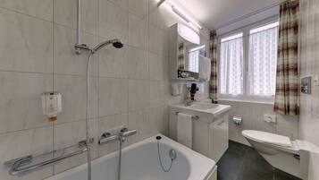 Un baño moderno con bañera, ducha, inodoro y lavabo.