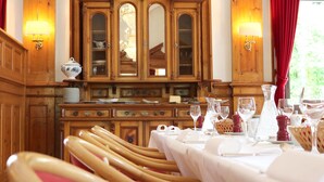 A dining area with wooden furniture, a large wooden cabinet, and two wall-mounted lamps. - Hotel Restaurant Schweizerhof (Val Muestair)