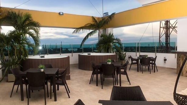Un patio al aire libre con mesas y sillas redondas, una silla colgante y plantas en macetas.