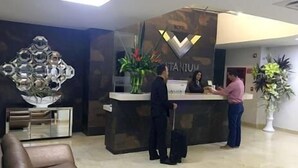 Un mostrador de recepción de hotel con diseño moderno, que incluye una decoración mural geométrica y una barra de recepción.