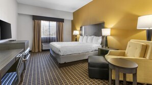Une chambre d’hôtel comprenant un lit, un bureau, une chaise, une télévision et deux lampes.