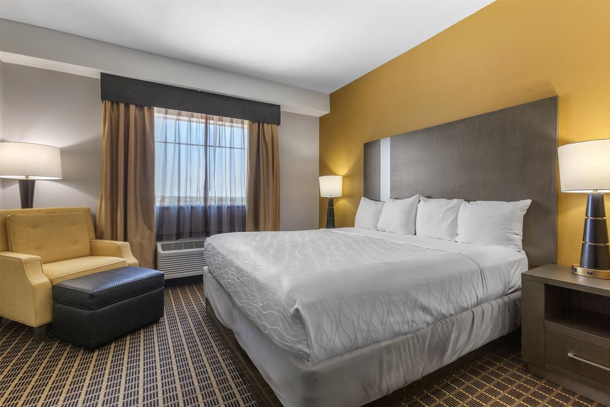 Una habitación de hotel con una cama grande, un sofá, una mesita y una lámpara.