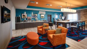 Un moderno vestíbulo de hotel con una decoración azul y naranja, un comedor y una kitchenette.