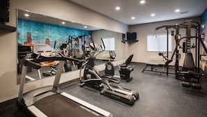 Un gimnasio con cintas de correr, elípticas y equipo de levantamiento de pesas.