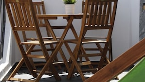 Un conjunto de mesa y sillas de madera en un balcón con una planta en maceta.