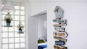 Una habitación con un ventanal grande, una cama con una colcha azul y una pared con un cartel con varias frases.