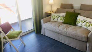 Una sala de estar con un sofá, una silla, una lámpara y vistas al exterior.