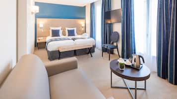 Une chambre d’hôtel comprenant un lit, un canapé, une petite table avec une bouilloire et un téléviseur.