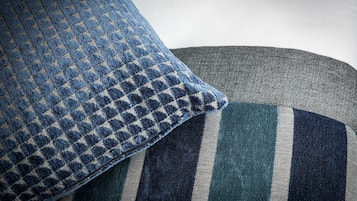A close-up of a blue and gray patterned pillow and a striped cushion.