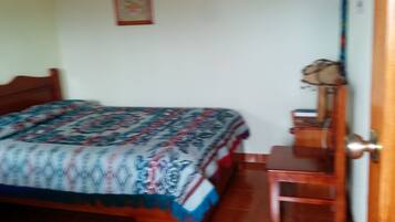 A bedroom with a bed, a wooden nightstand, a chair, and a door.