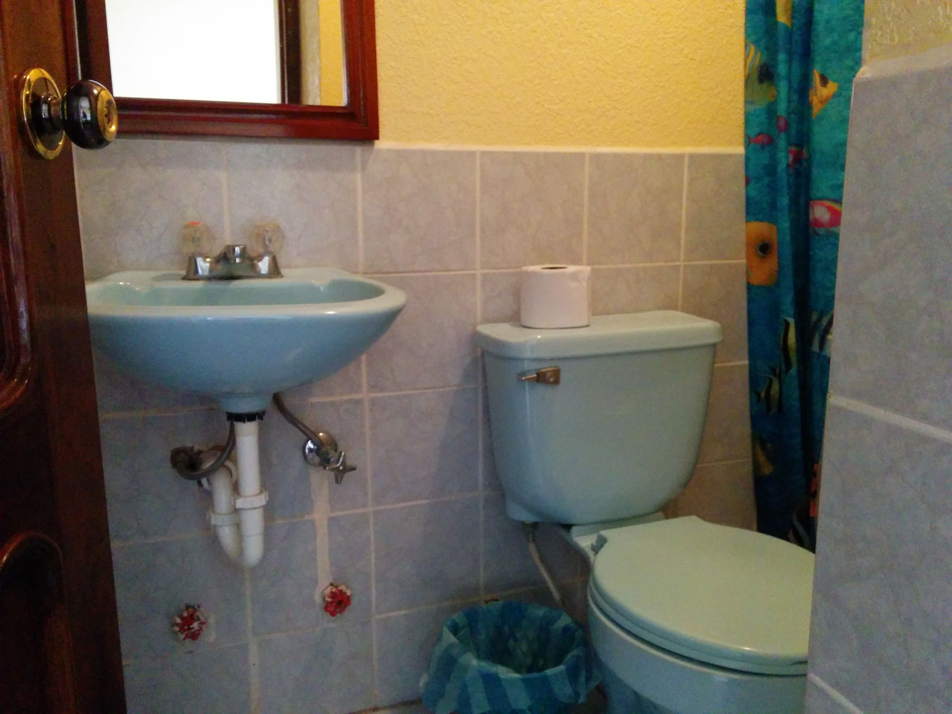 Un baño con lavamanos, inodoro y un cubo de basura.