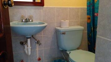 Un baño con lavamanos, inodoro y un cubo de basura.