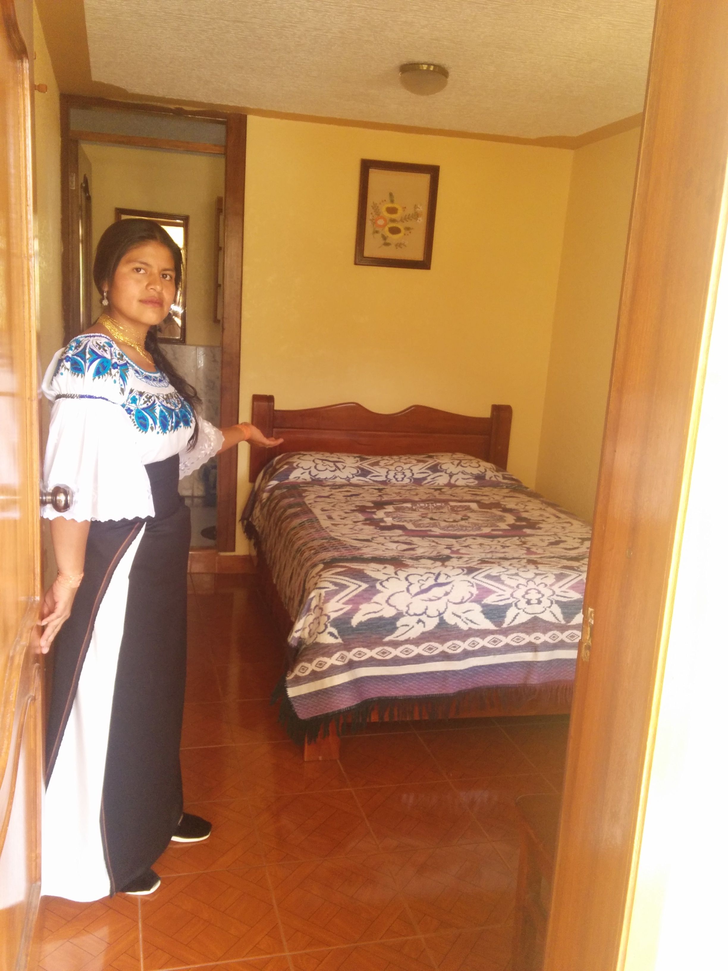 A bedroom with a bed, a wooden door, and a wall with a framed picture.