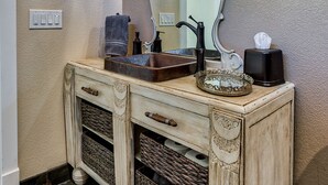 A bathroom vanity with a mirror, a chandelier, and a decorative wall piece. - Hope Inn Redding (Redding)