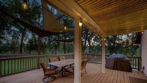 A wooden deck with a covered seating area, a table, and chairs. - Hope Inn Redding (Redding)