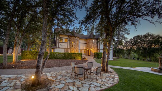 A stone patio with outdoor furniture, surrounded by a well-maintained lawn and trees. - Hope Inn Redding (Redding)