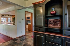 A kitchen with a central island, a dark wooden cabinet with glass doors, and a decorative vase on the upper shelf.