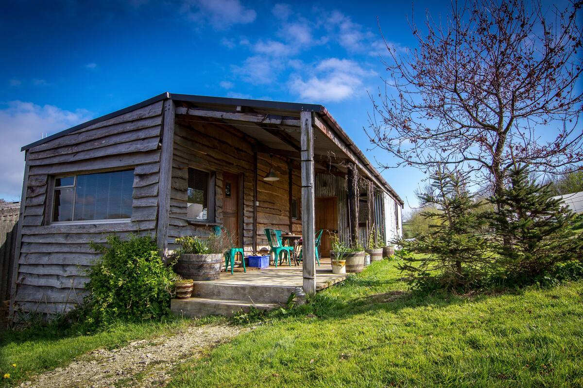 A rustic cabin with a porch, outdoor seating, and a small garden.