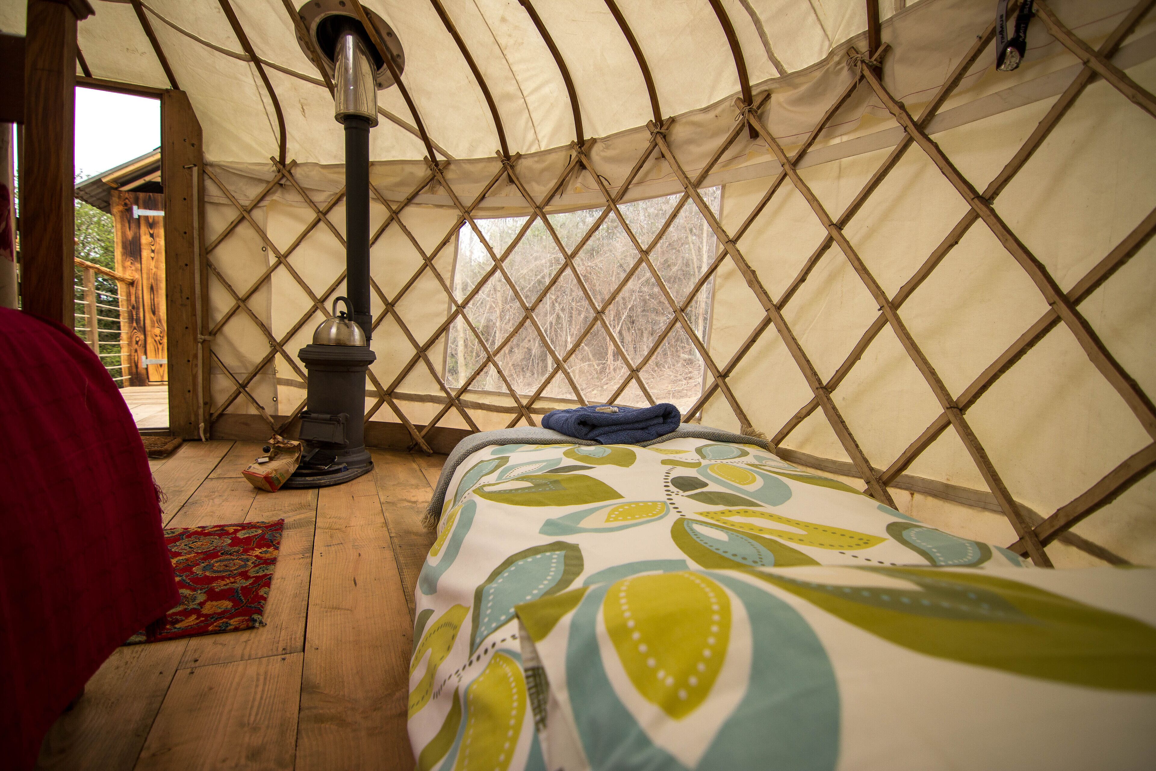 A cozy interior of a yurt with a bed, a heater, and a view of the outside.