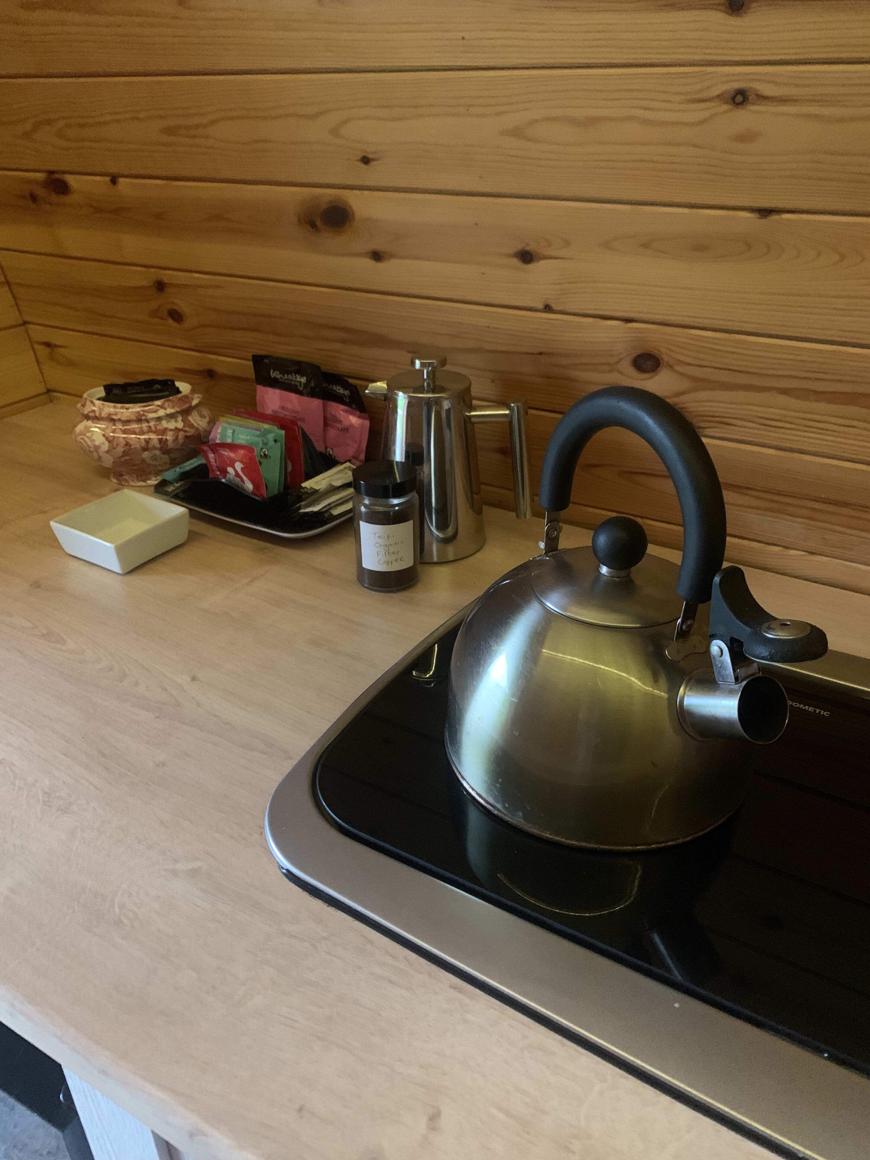 A kitchen with a kettle on the stove, a coffee maker, and a tea kettle on the counter.