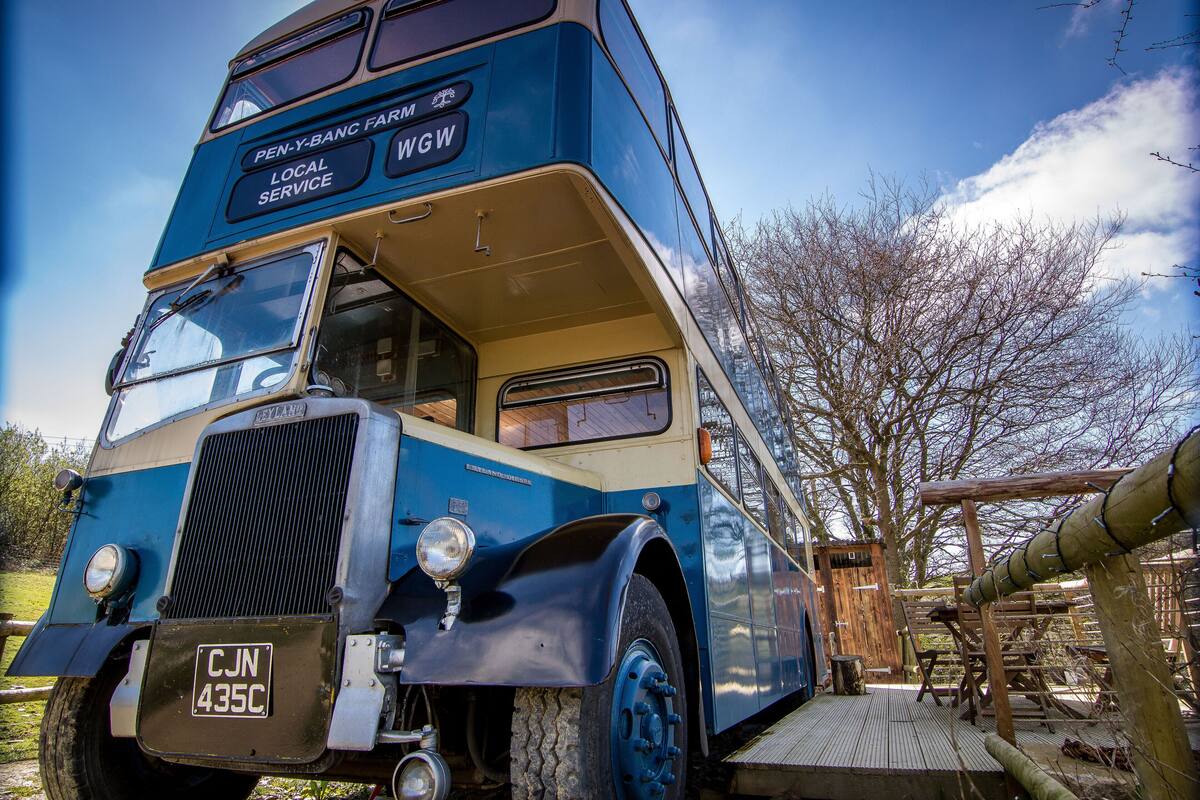 A vintage double-decker bus parked outdoors with a license plate visible.