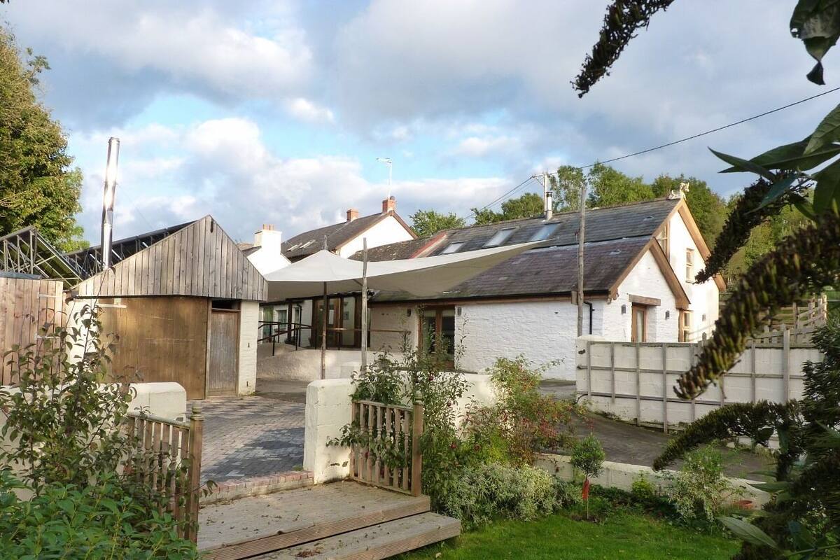 A residential property with a garden, a wooden fence, and a white building with a sloped roof.