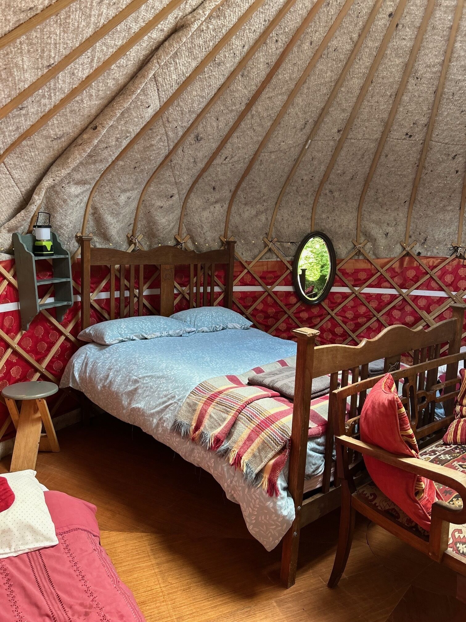 A cozy interior of a traditional yurt with a bed, wooden furniture, and a small shelf.