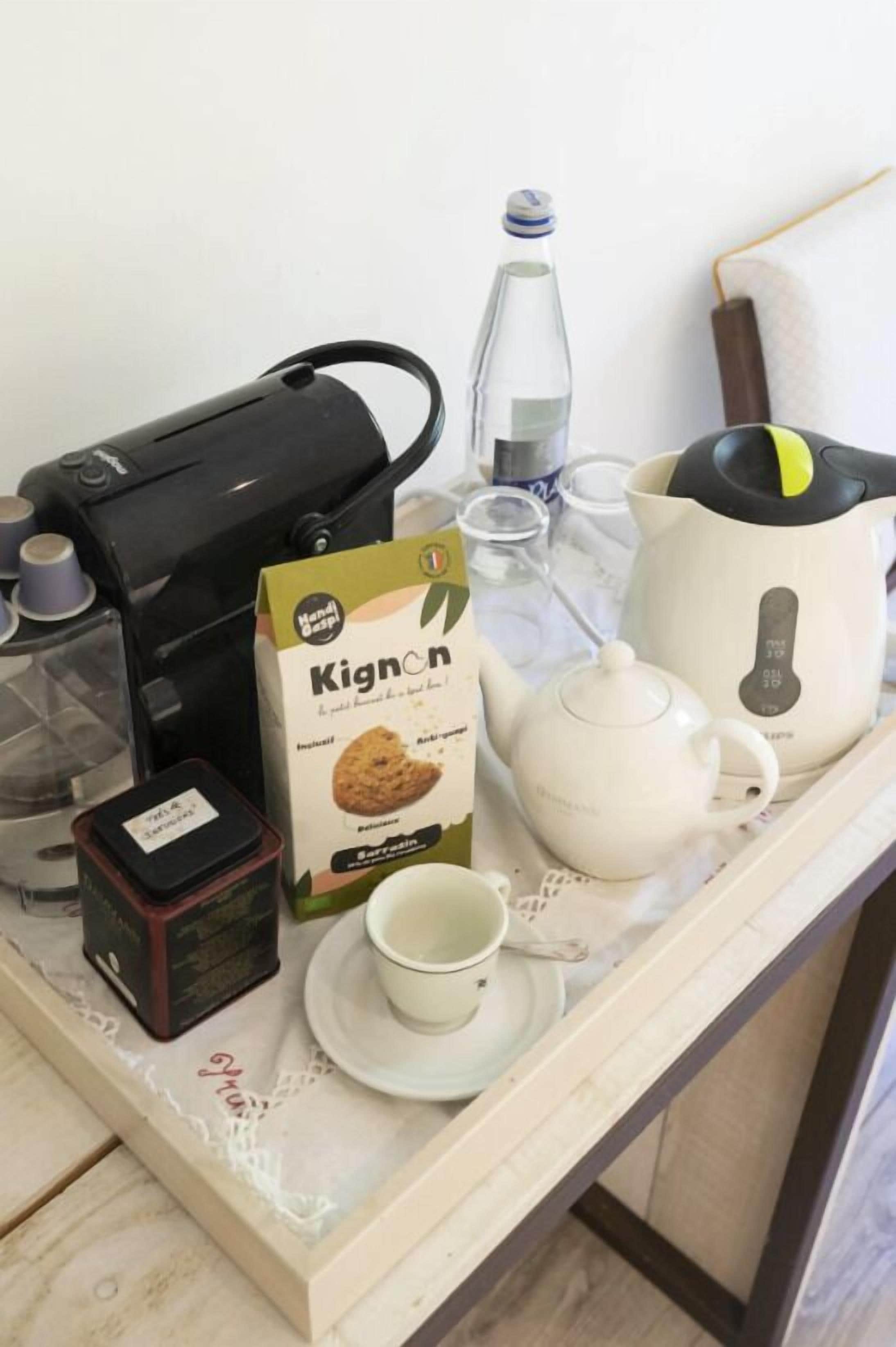 Una bandeja con una cafetera, una caja Kicon, un hervidor, una taza y una botella de agua.