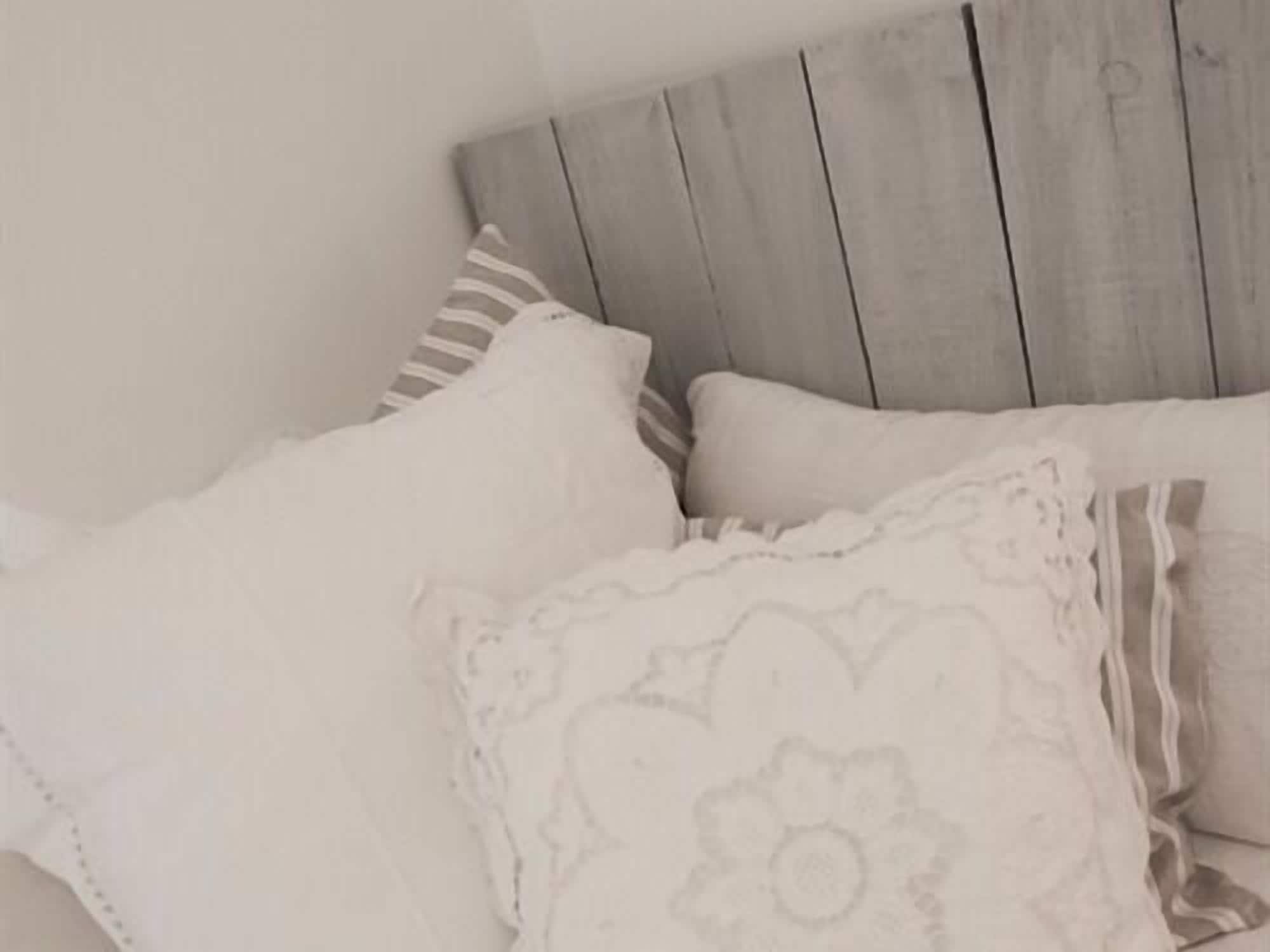 A bed with a wooden headboard, multiple pillows, and a white blanket.