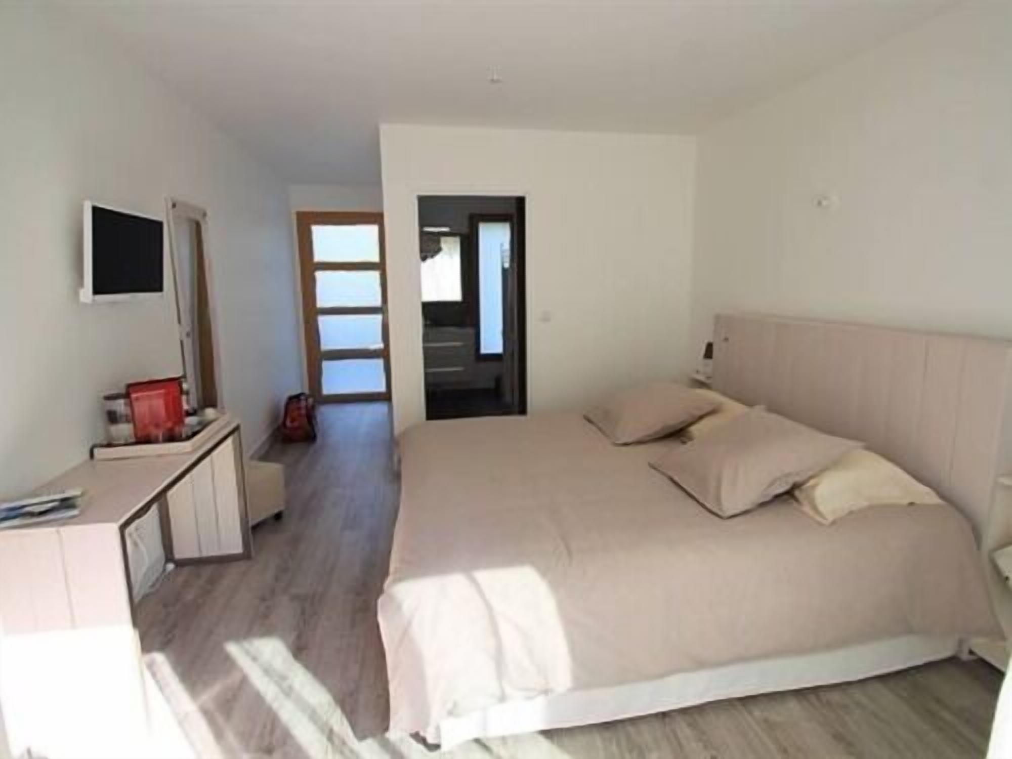 A bedroom with a bed, a desk, and a television.