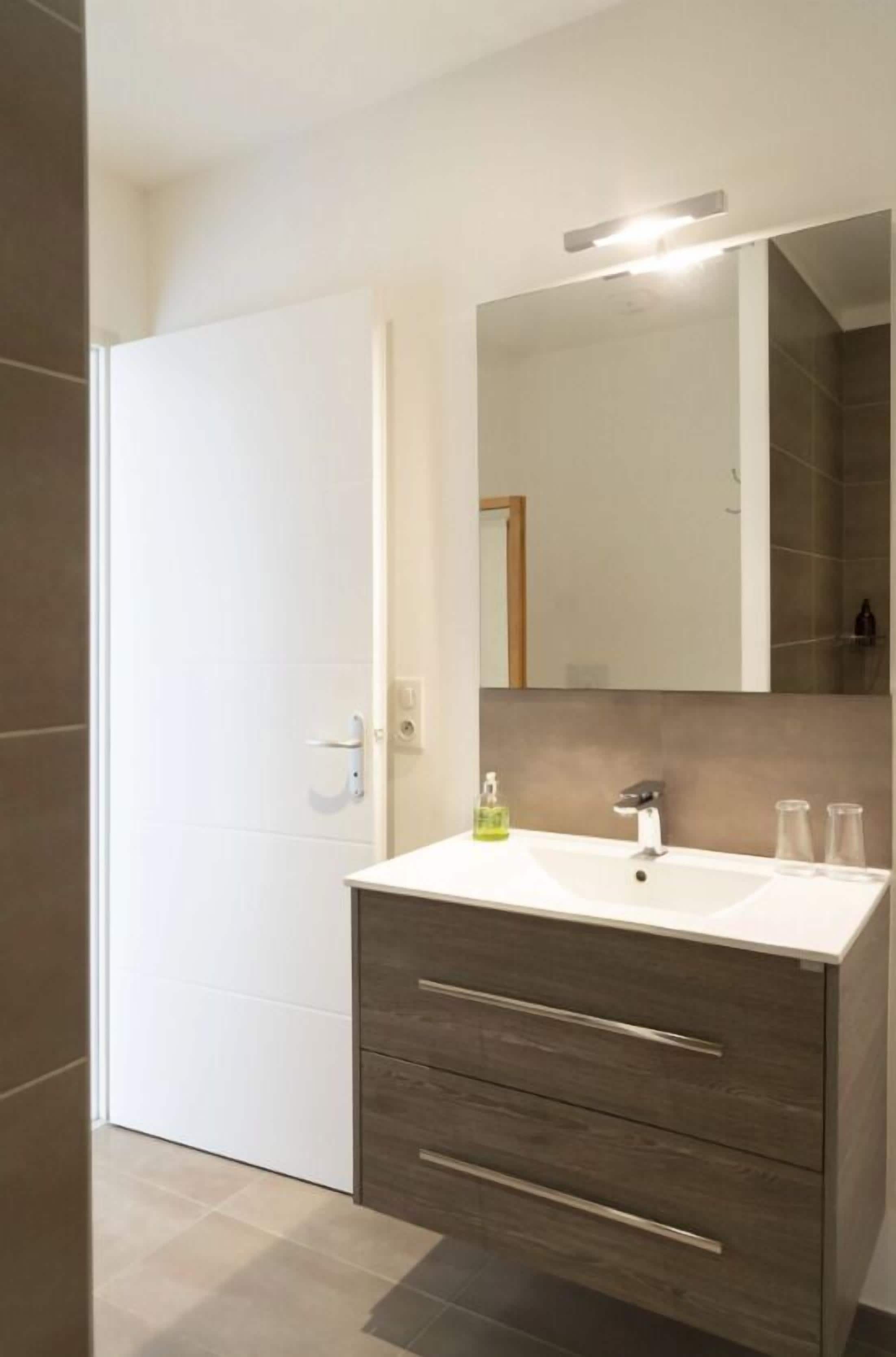 A modern bathroom with a white sink, dark wood vanity, and a large mirror.