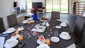 A dining area with a table set for breakfast, including plates, cups, and a vase of flowers. - La Balade des Marais (Saint-Molf)