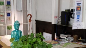 Una mesa de recepción con un cartel verde, una estatua de Buda y un letrero que prohíbe el ingreso de alcohol.