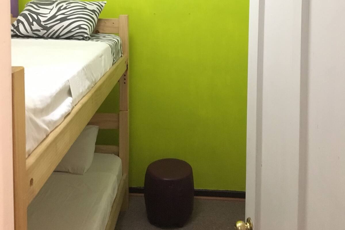 Una habitación pequeña con una cama doble, una pared verde y una puerta con ventana.