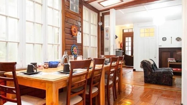 Un comedor con una mesa y sillas de madera, una cafetera y un adorno en la pared.