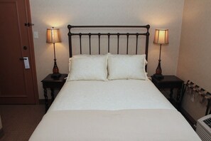 A standard hotel room with a single bed, two bedside tables with lamps, a door, and a radiator.