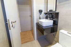 Um banheiro moderno com pia branca, bancada preta e vaso sanitário.
