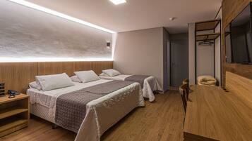 Quarto de hotel moderno com duas camas, um guarda-roupa de madeira, um espelho e uma mesa de cabeceira com telefone.