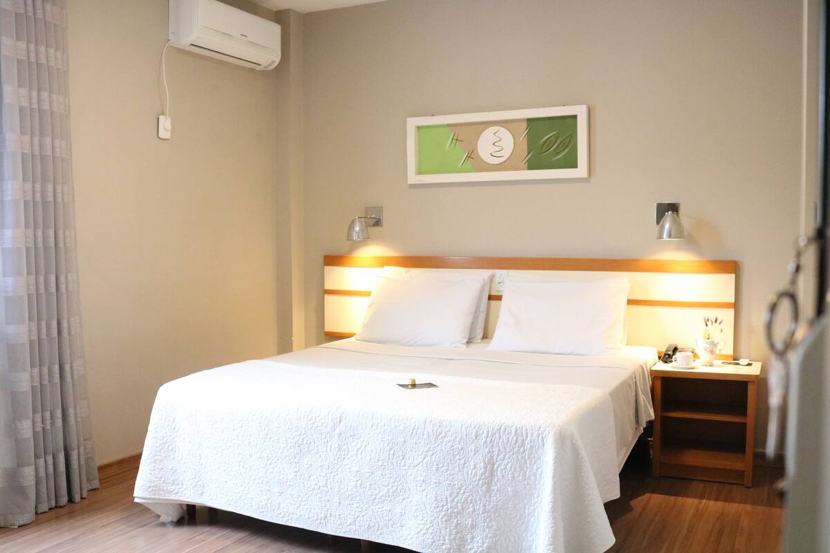 Une chambre d’hôtel équipée d’un lit, d’une table de chevet, d’une lampe et d’un climatiseur fixé au mur.